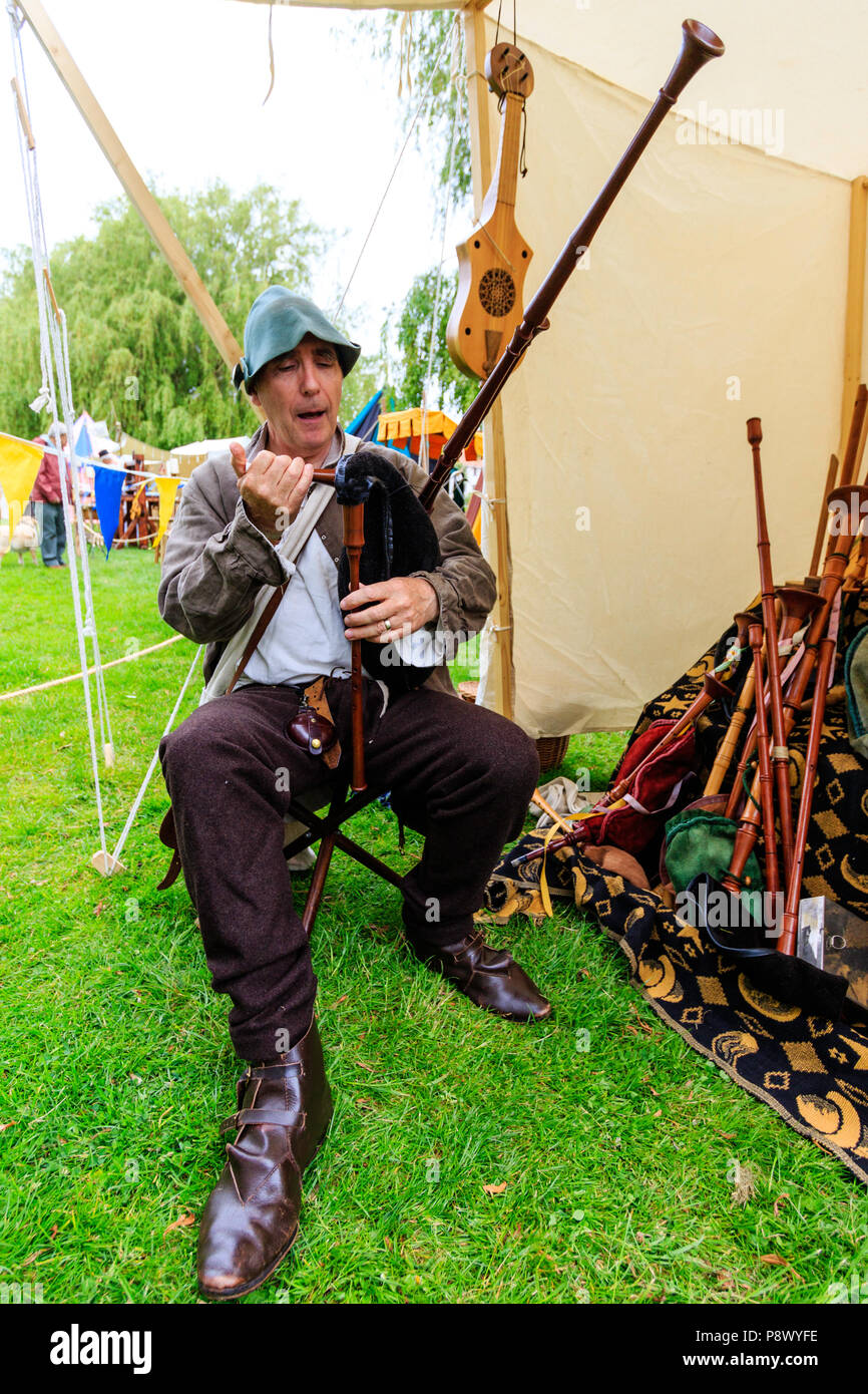 Rievocazione storica, storia vivente evento. Uomo caucasico in costume medievale di un menestrello, seduti all'aperto e tenendo cornamuse. Foto Stock