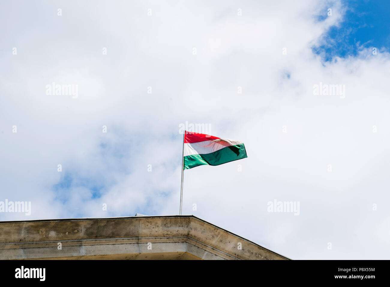 Vista la bandiera ungherese che ondeggia con un cielo nuvoloso sullo sfondo Foto Stock