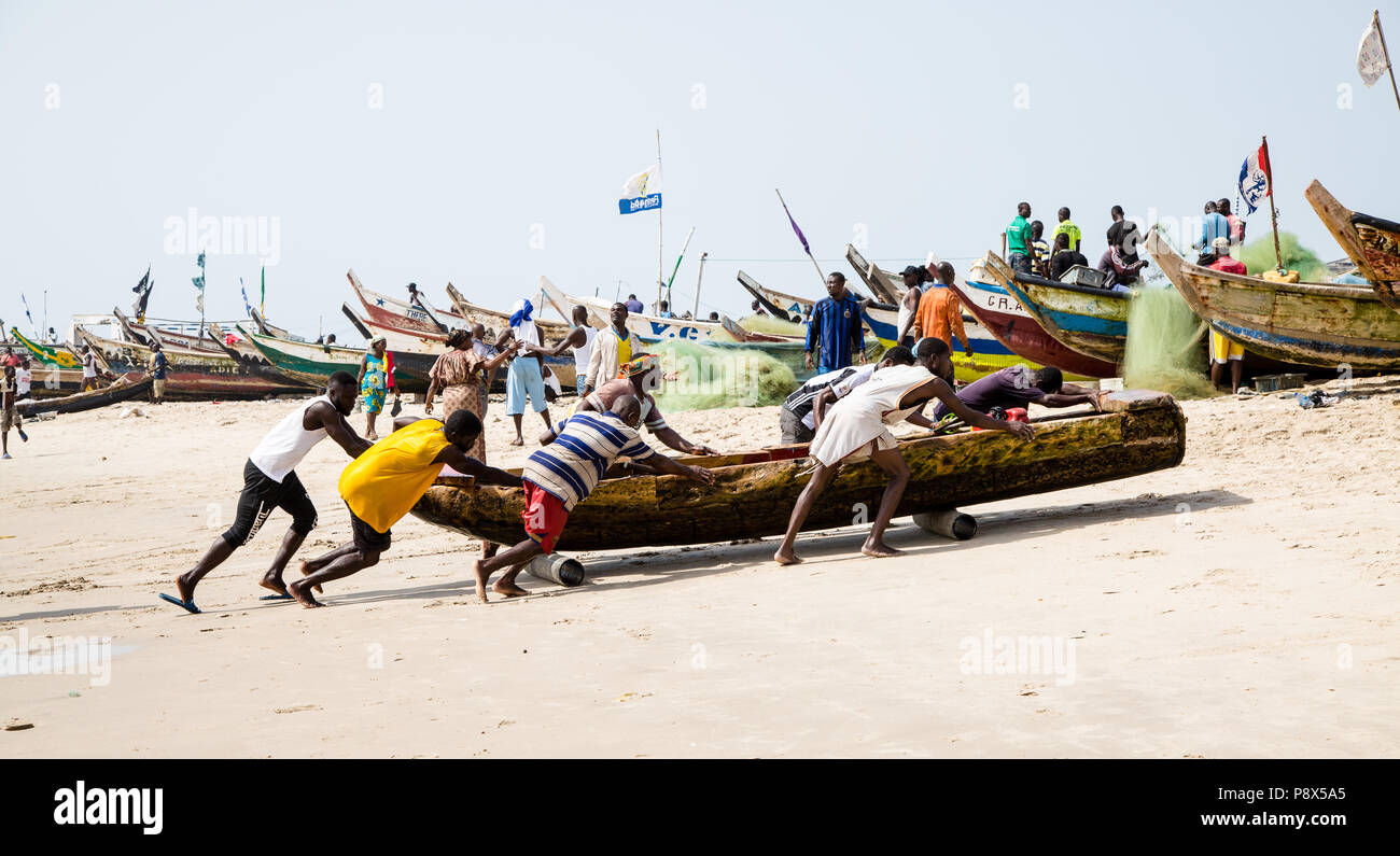 Pescatore che trasporta la barca da pesca sulla spiaggia, Accra, Ghana Foto Stock