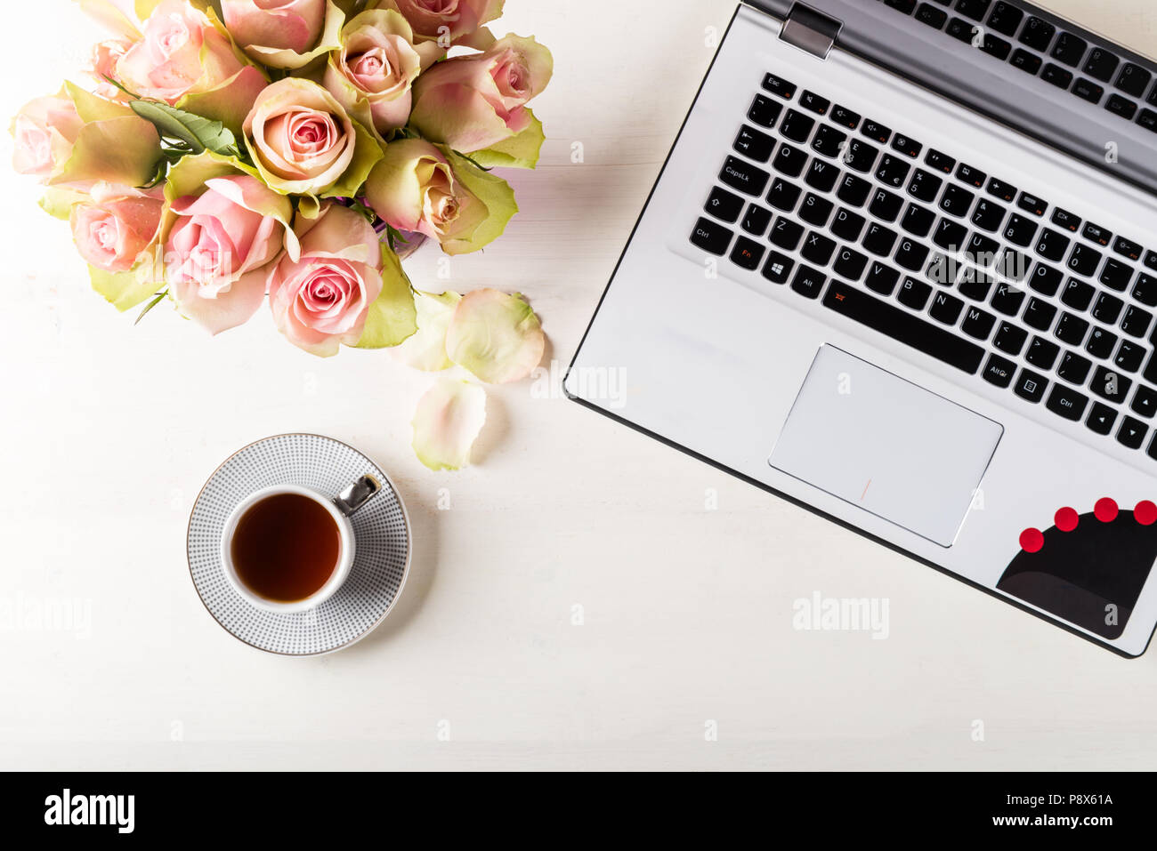 Business femminile mockup con laptop, bouquet di rose e la tazza di caffè, flatlay bianco su sfondo di legno con copyspace Foto Stock