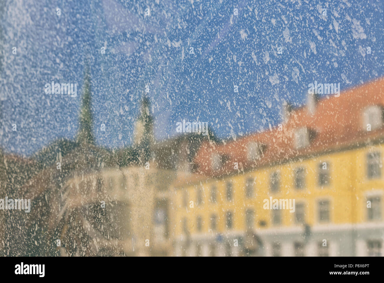 La riflessione dell'edificio giallo e le torri della città nella finestra di dipingere su uno sfondo di cielo blu. Sfocata Foto Stock