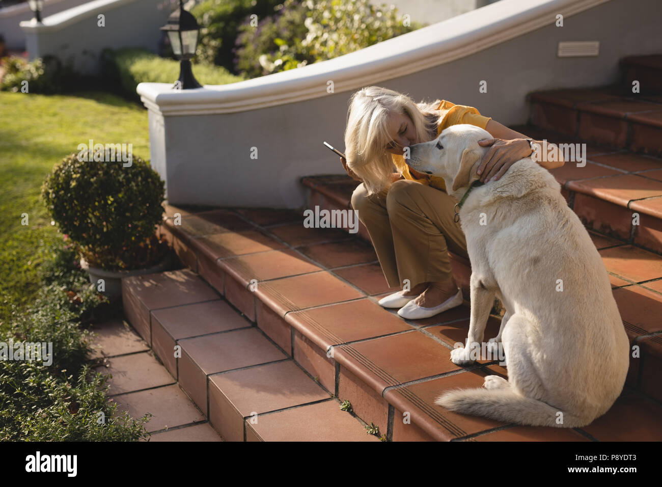 Senior donna baciare cane su fasi di ingresso Foto Stock