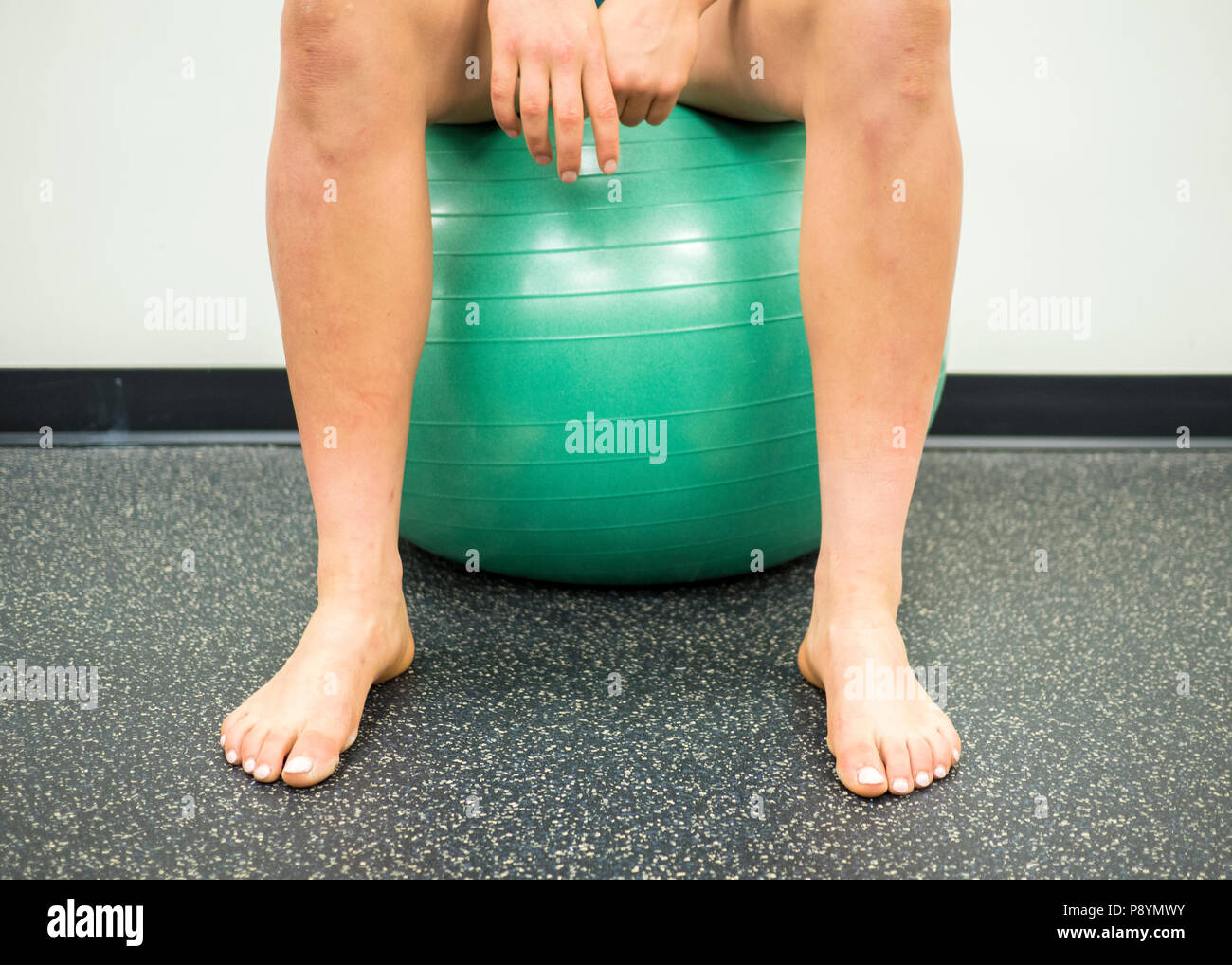 Atleta seduto su un verde palla ginnica prendendo una pausa tra i suoi esercizi Foto Stock