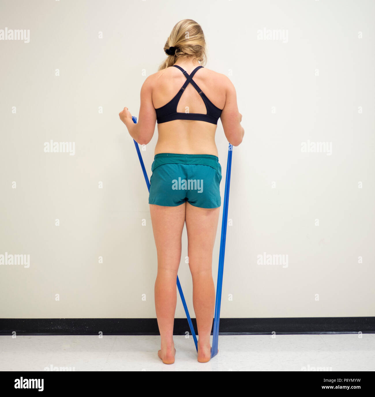 Vista posteriore di una femmina di atletica utilizzando una resistenza con elastici Theraband band per esercizio Foto Stock