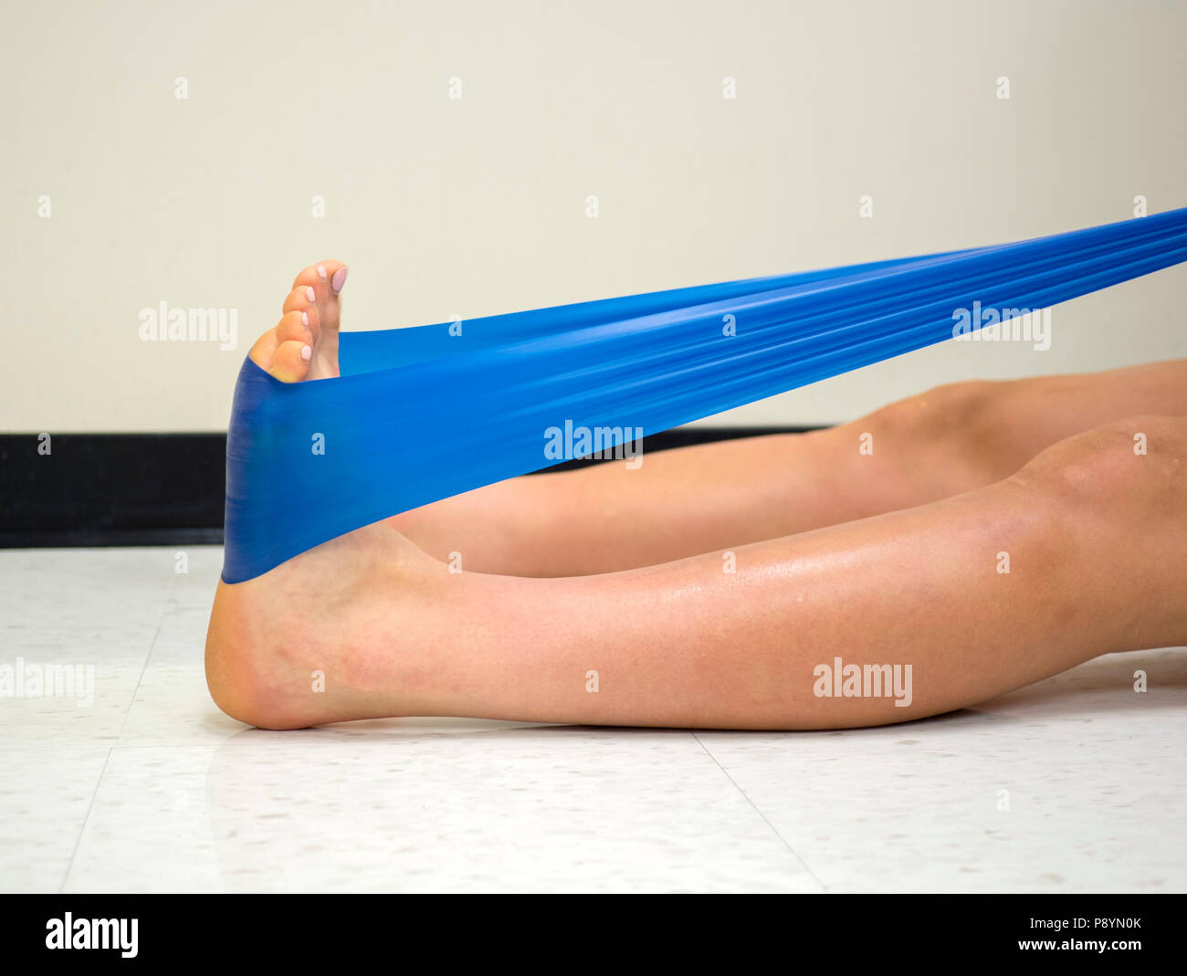 Gamma atleta usando un esercizio con elastici Theraband band per rafforzare la sua caviglia Foto Stock
