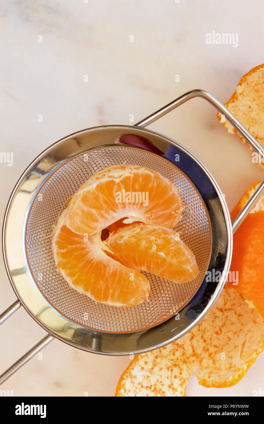 Mandarin segmenti in un setaccio da cucina. Foto Stock