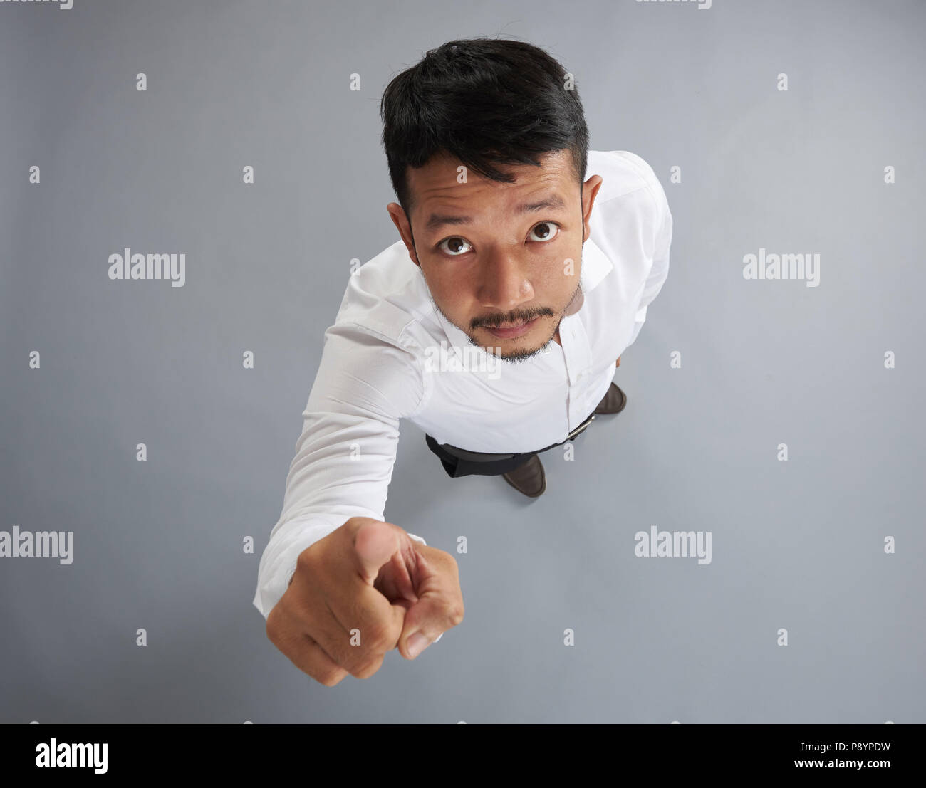 Uomo asiatico il punto con il dito isolato su sfondo grigio sopra vista superiore Foto Stock
