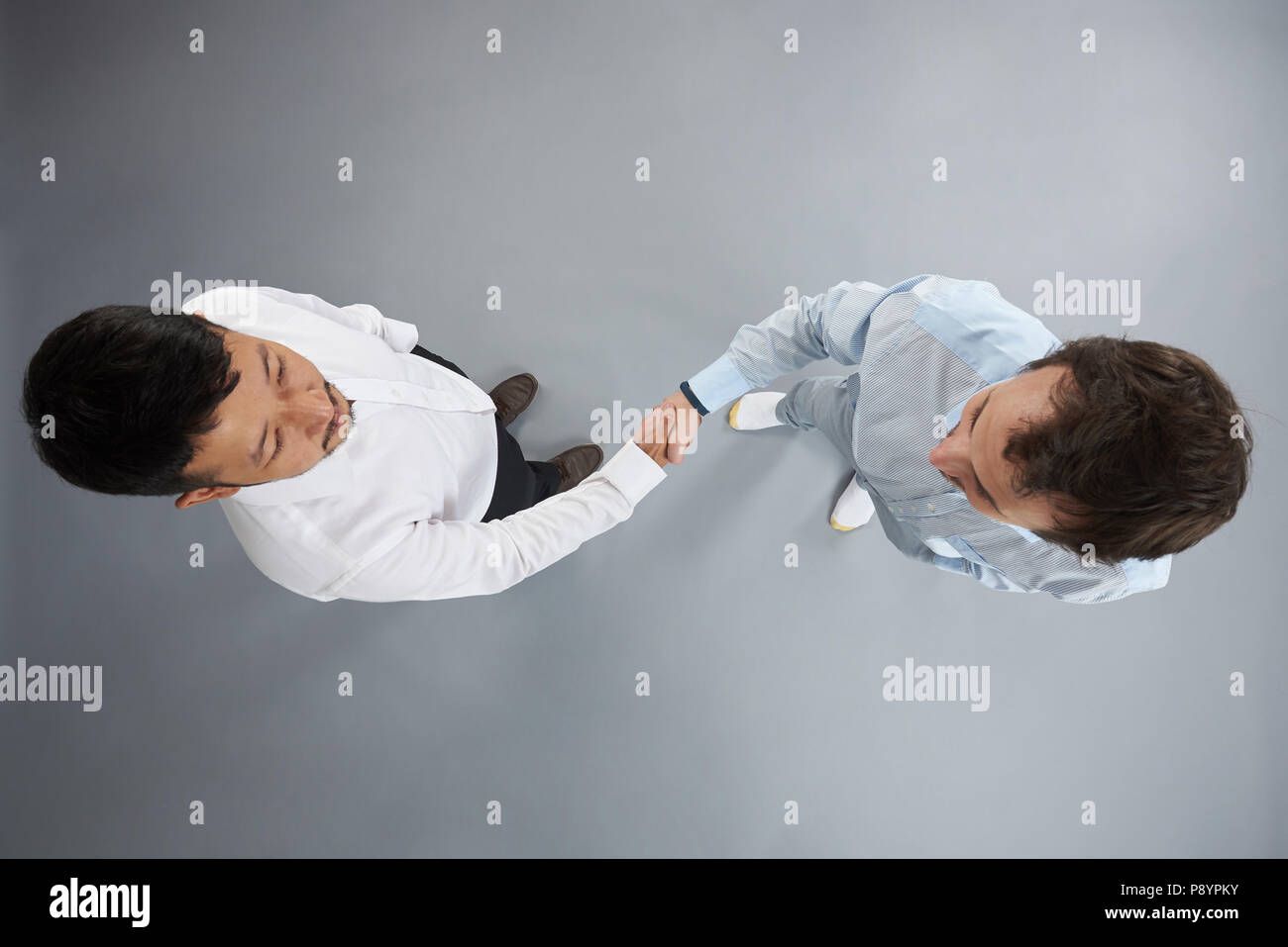 Due uomo sopra di handshake vista dall'alto isolato su sfondo grigio Foto Stock