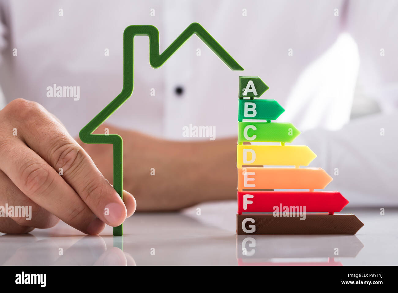 Commercianti di mano azienda profilo del modello di casa con efficienza energetica tasso sulla scrivania riflettente Foto Stock