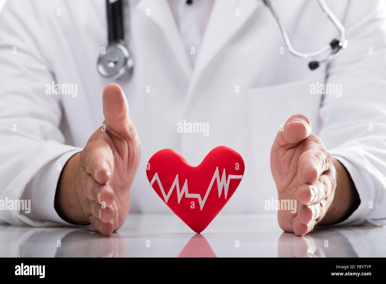 Medico della mano rosso di protezione frequenza cardiaca sulla scrivania Foto Stock