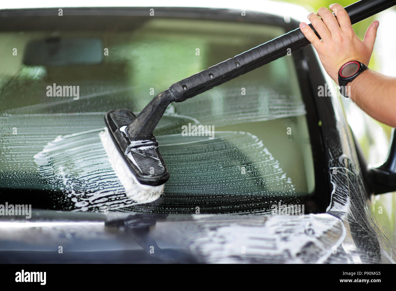 Usando una spazzola per lavare un auto in macchina su un impianto di  lavaggio su soleggiate giornate estive Foto stock - Alamy