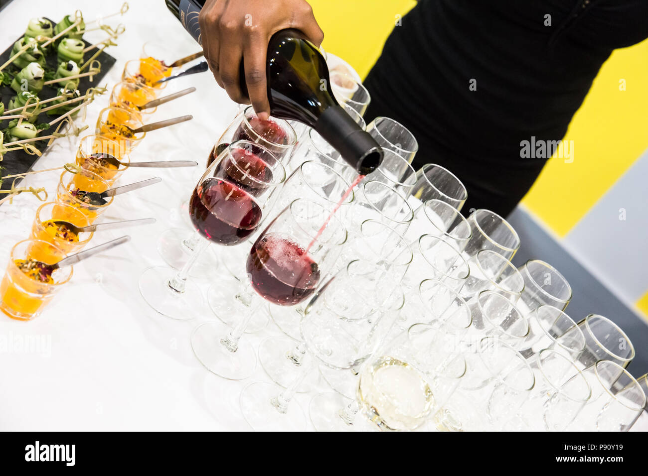 Cameriera versando il vino rosso in bicchieri a tavolo buffet con panno bianco Foto Stock