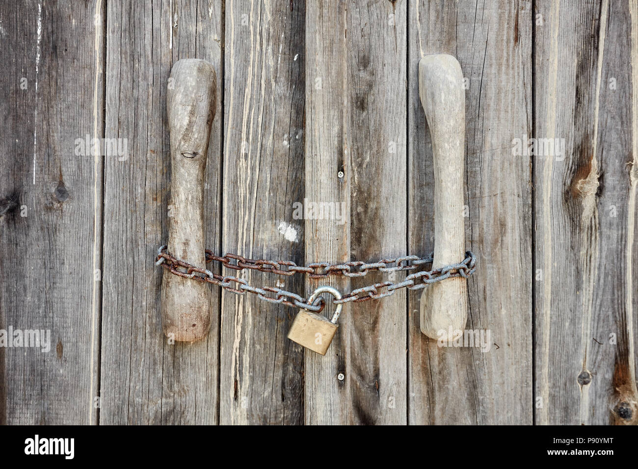 Vista ravvicinata di una vecchia porta di legno bloccato con rusty catena e lucchetto Foto Stock