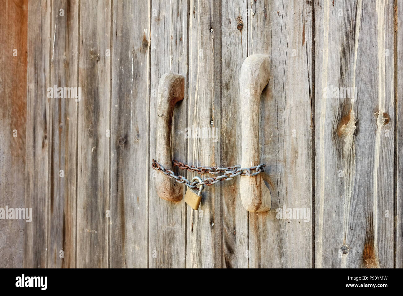 Vista ravvicinata di un vecchio fienile in legno porta bloccata con rusty catena e lucchetto Foto Stock