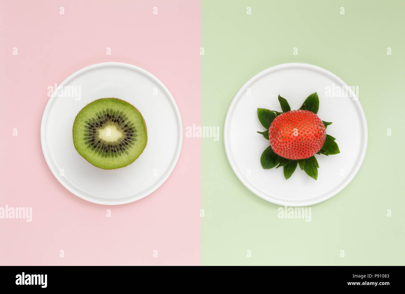 Un Kiwi e una fragola sul duo colore di sfondo Foto Stock