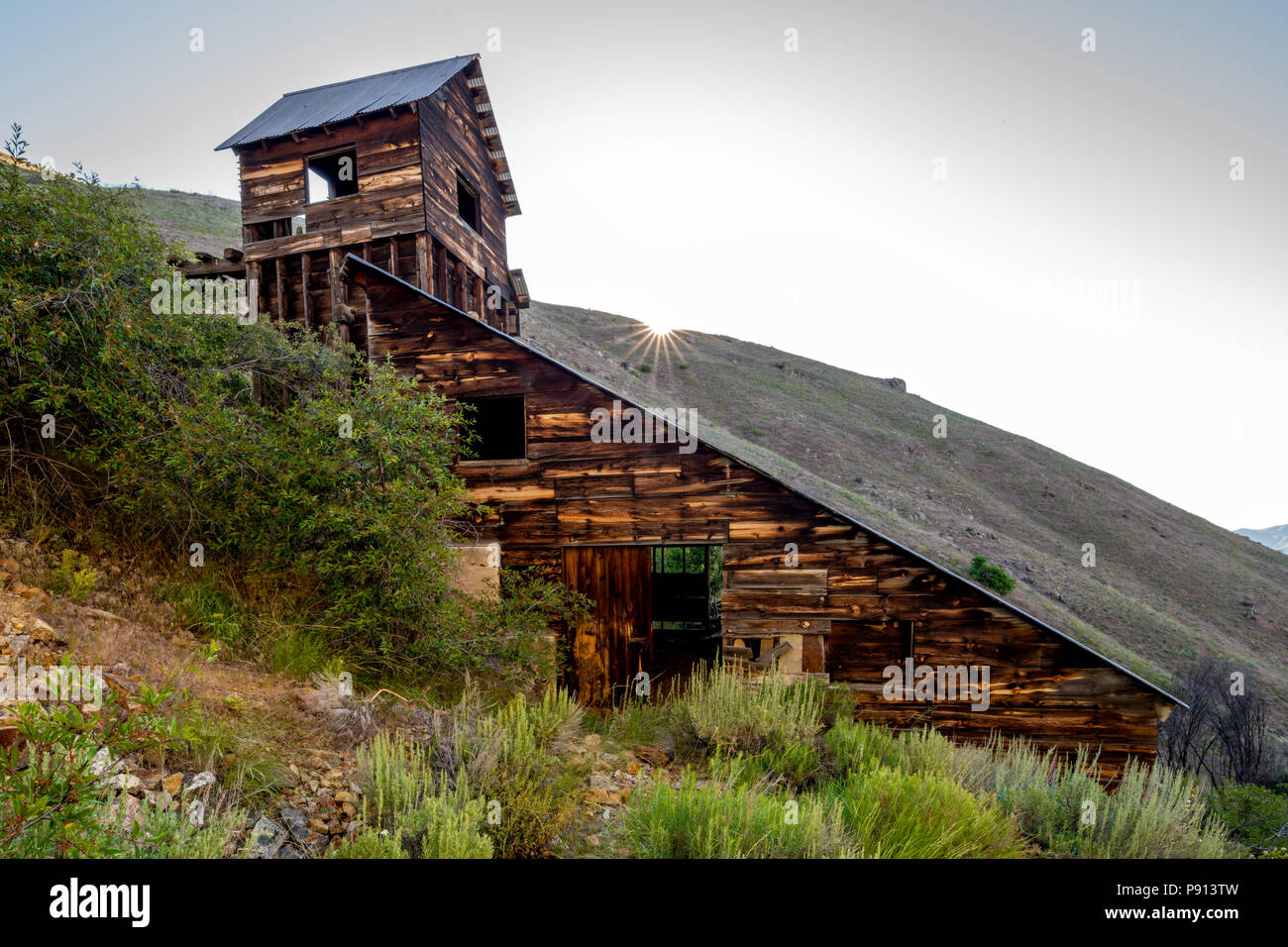 Oro ming edificio di legno con stagno rook e sun risuing appena oltre la cresta Foto Stock