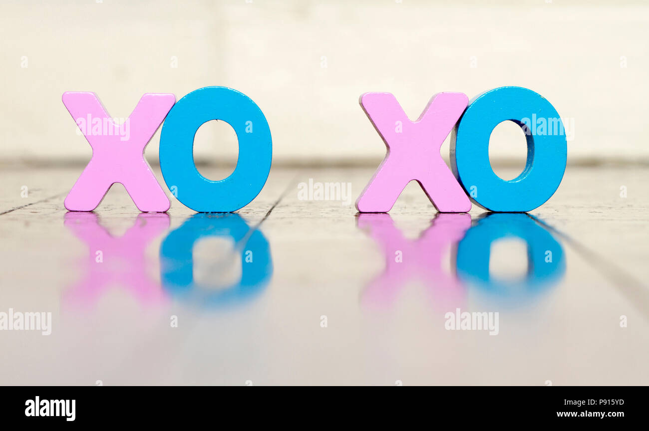 XO XO lettere in legno su un vecchio pavimento in legno con la riflessione colore soffice Foto Stock