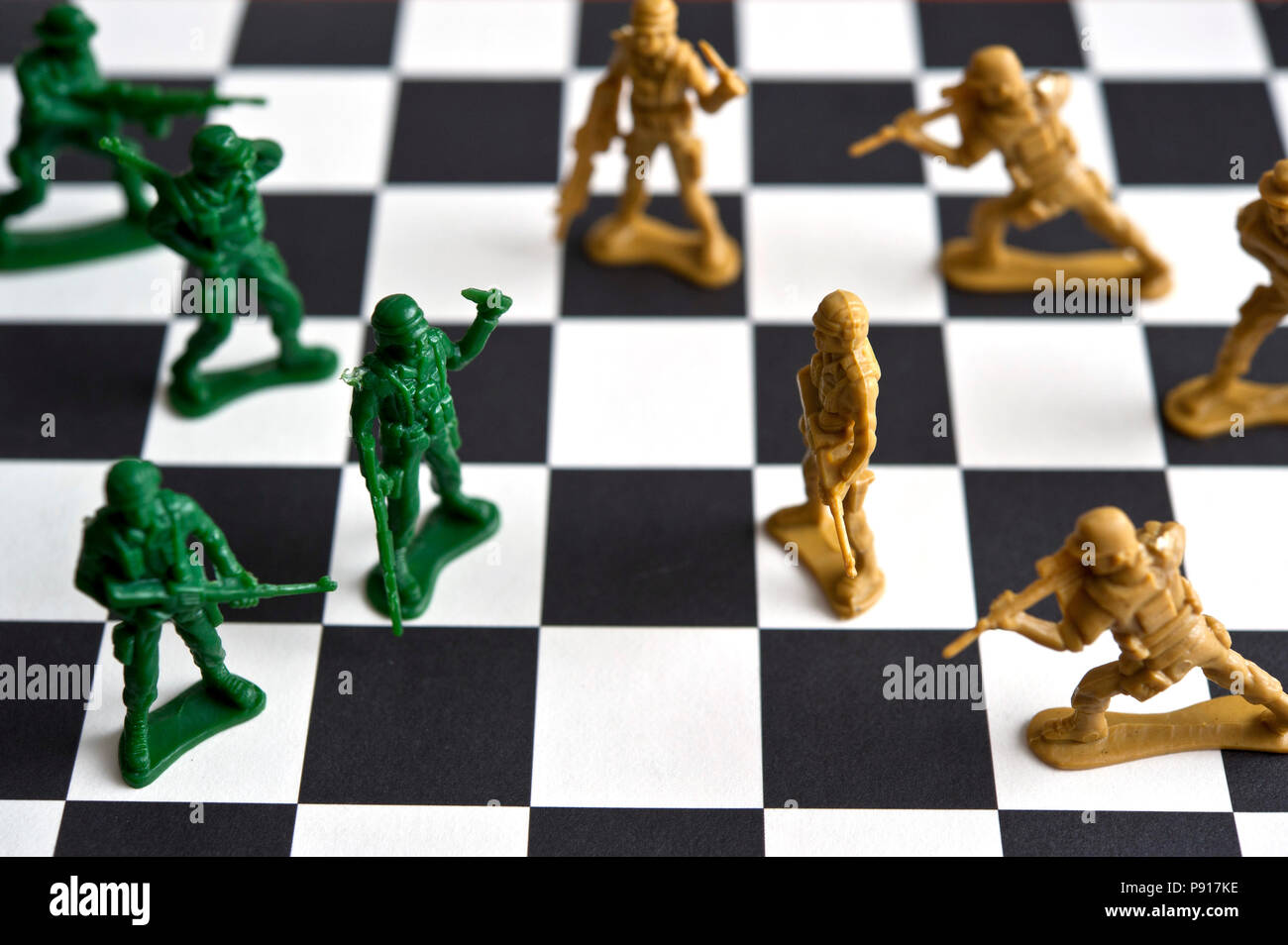 Due eserciti di giocattolo di plastica soldati affacciati su una scacchiera Foto Stock