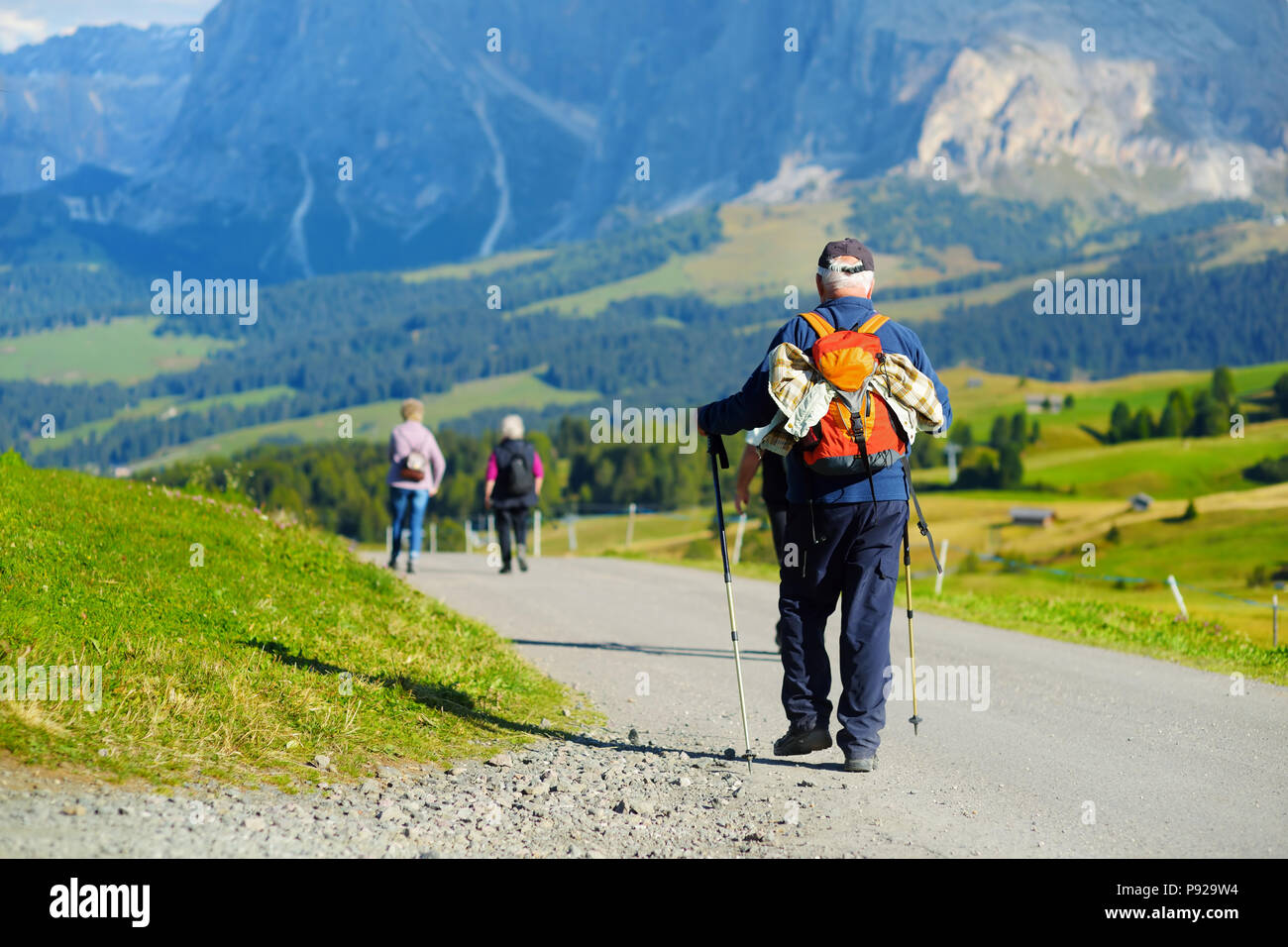 I turisti escursioni in Alpe di Siusi, il più grande ad alta altitudine prato alpino in Europa, incredibili montagne rocciose sullo sfondo. Alto Adige Provincia di Foto Stock