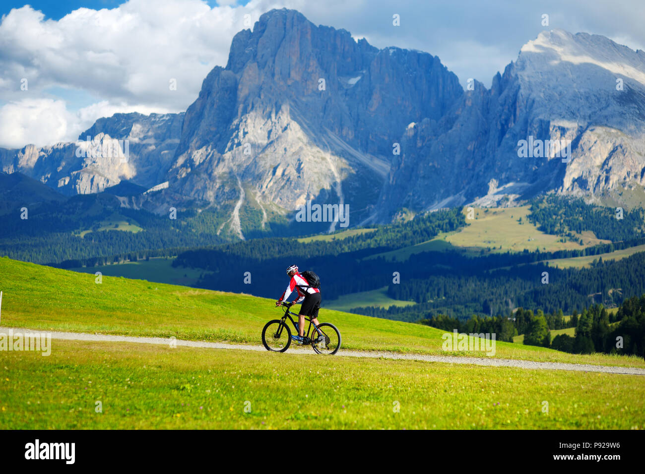 I turisti in bicicletta in Alpe di Siusi, il più grande ad alta altitudine prato alpino in Europa, incredibili montagne rocciose sullo sfondo. Alto Adige Provincia di Foto Stock