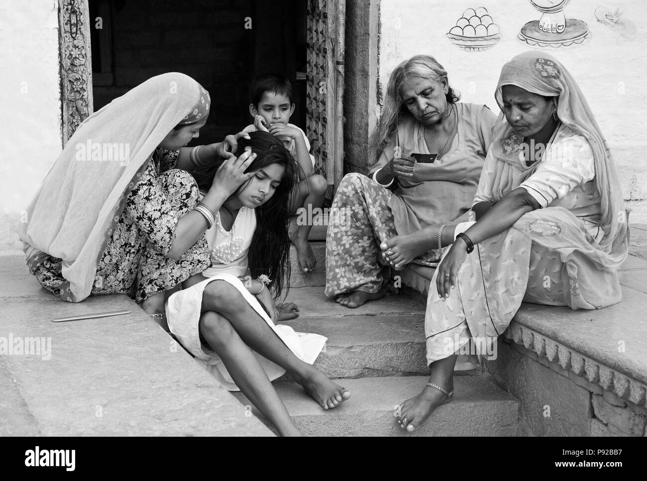 Una donna di Rajasthani stallieri le sue figlie capelli sui gradini della sua casa di pietra arenaria della città d'oro - JAISALMER, INDIA Foto Stock