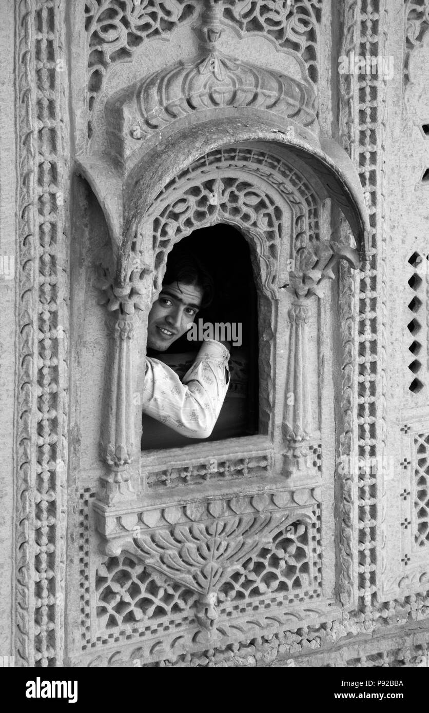 Un ragazzo indiano si affaccia una mano arenaria intagliata nella finestra il MAHARAJA'S PALACE si trova all'interno di JAISALMER FORT - Rajasthan, India Foto Stock