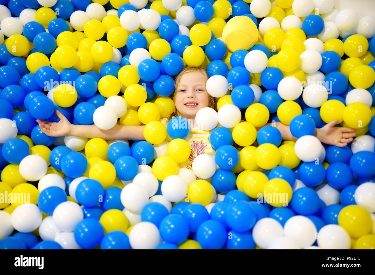 Felice bambina divertendosi in palla in buca kids giochi al coperto Centro. Bambini  che giocano con le palle colorate in parco giochi piscina di palline.  Attività giocattoli per litt Foto stock -