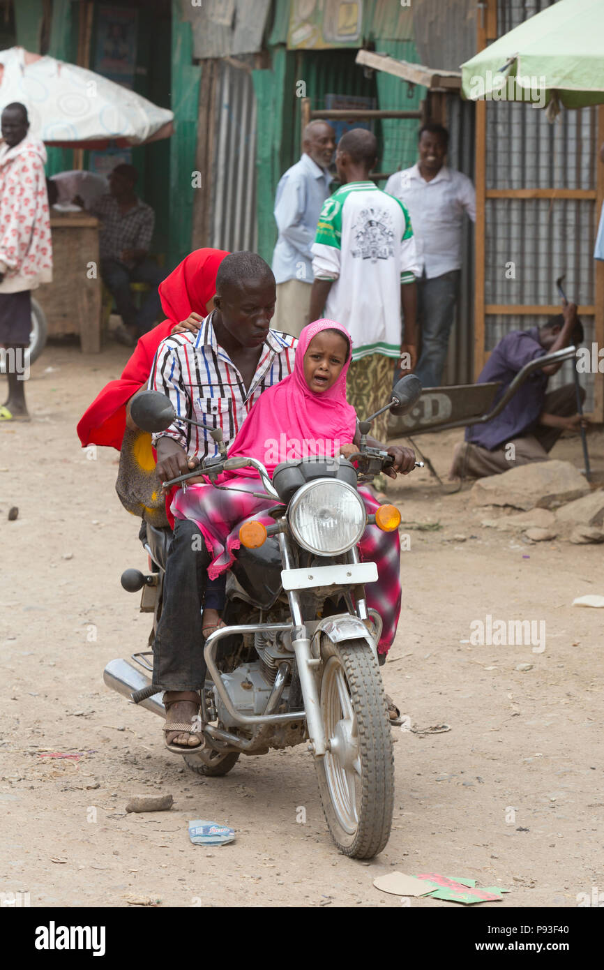 Kakuma, Kenya - Scene di strada. Una famiglia nucleare rigidi su un motociclo su una strada sterrata. Foto Stock