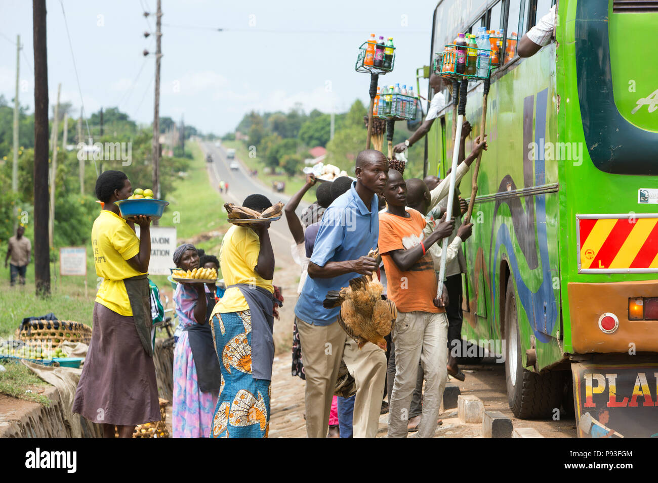 Kamdini, Uganda - ad una fermata del bus, battenti mercanti offrono ai viaggiatori un " commuter " bus per la vendita. Foto Stock