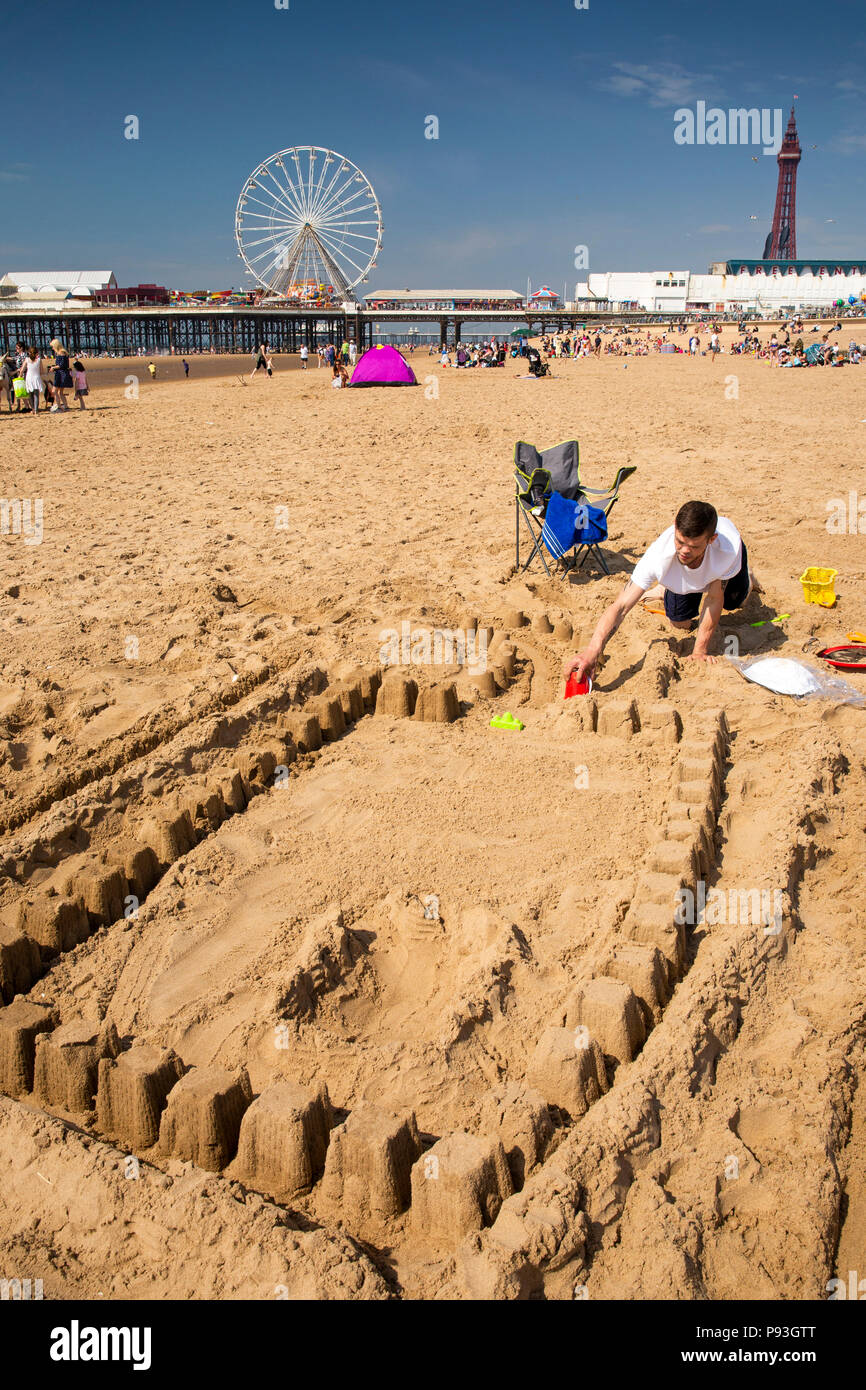 Regno Unito, Inghilterra, Lancashire, Blackpool, spiaggia adulto visitatore rendendo sandcastle dal molo centrale Foto Stock