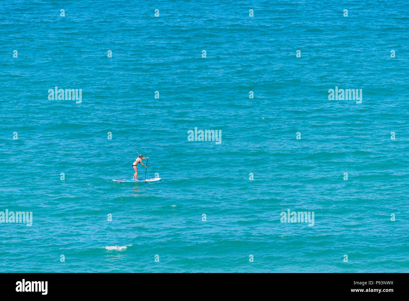 Una donna su una racchetta in pensione il mare. Foto Stock