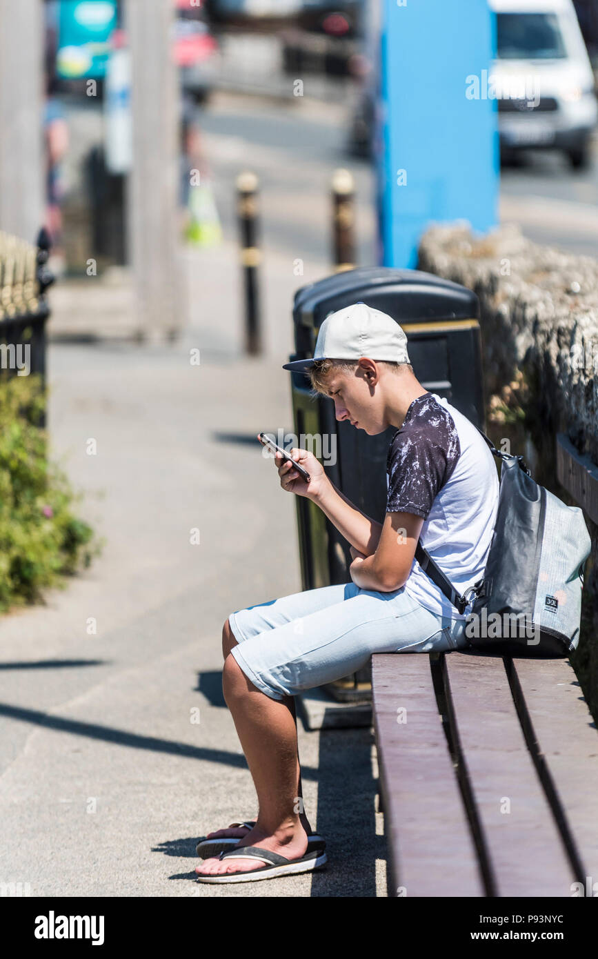 Un giovane ragazzo adolescente assorbiti nel suo smartphone. Foto Stock