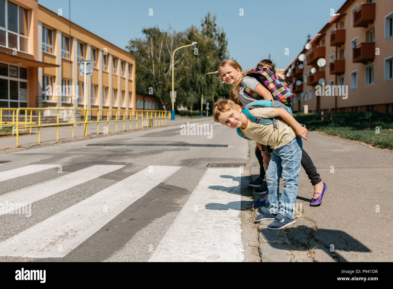 Compagni di scuola in un crosswalk guardando a destra e a sinistra prima di attraversare. I bambini alle strisce pedonali guardando intorno e sta tentando di attraversare una strada. Foto Stock