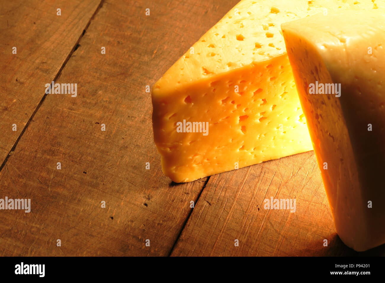 Due pezzi di formaggio giacente sulla tavola di legno. Piacevole effetto di illuminazione e spazio di copia Foto Stock