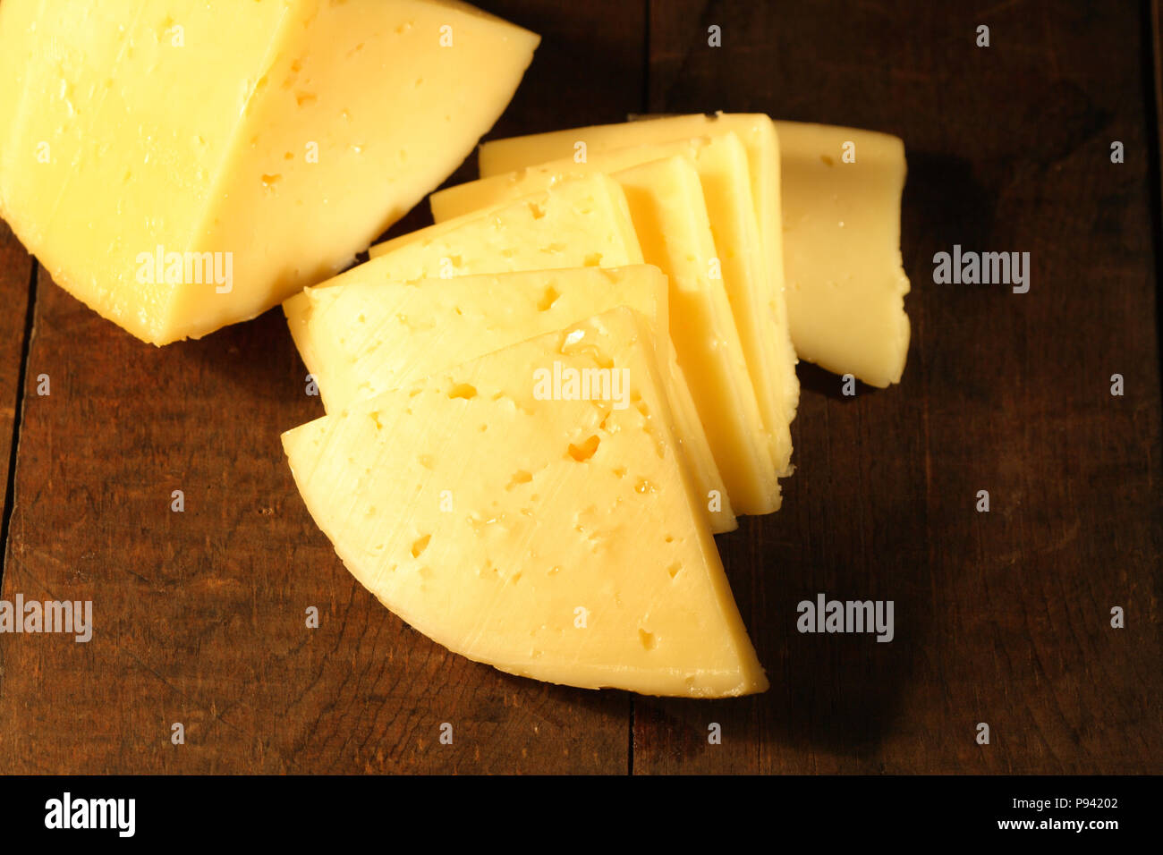 Vista dettagliata del formaggio a fette giacente sul tavolo di legno Foto Stock