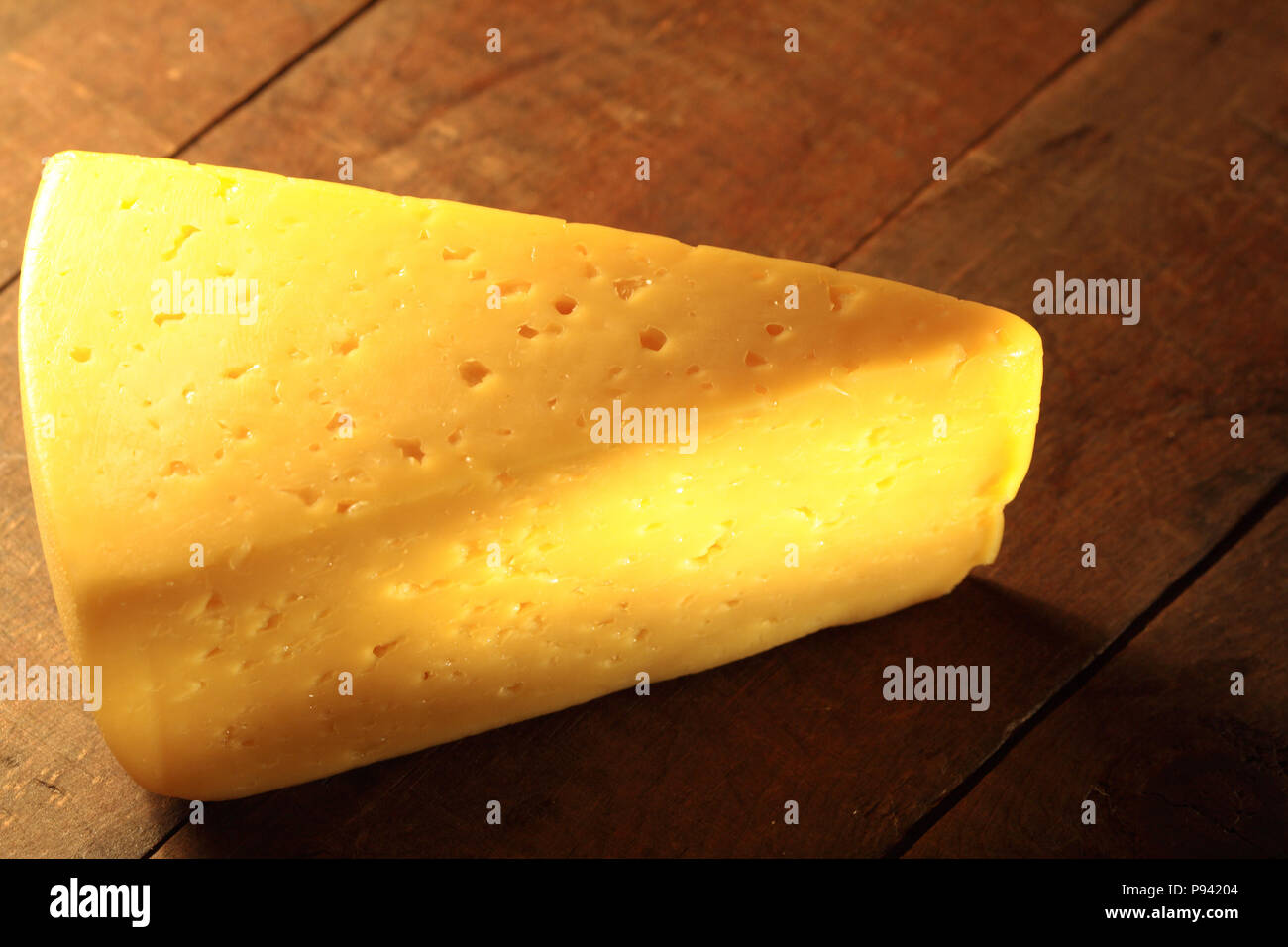 Primo piano del pezzo di formaggio che giace sul tavolo di legno Foto Stock
