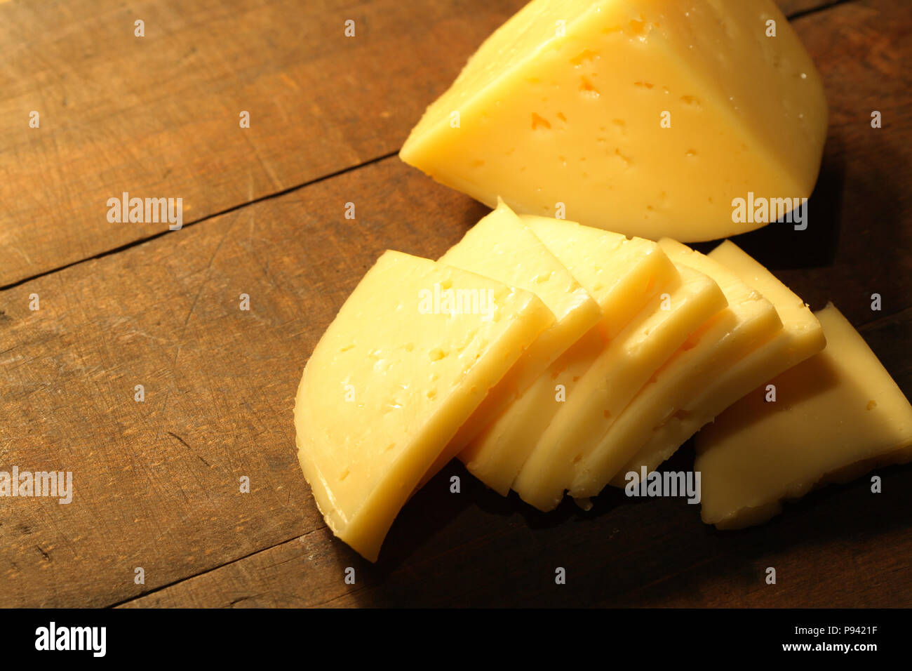 Vista dettagliata del formaggio a fette giacente sul tavolo di legno Foto Stock