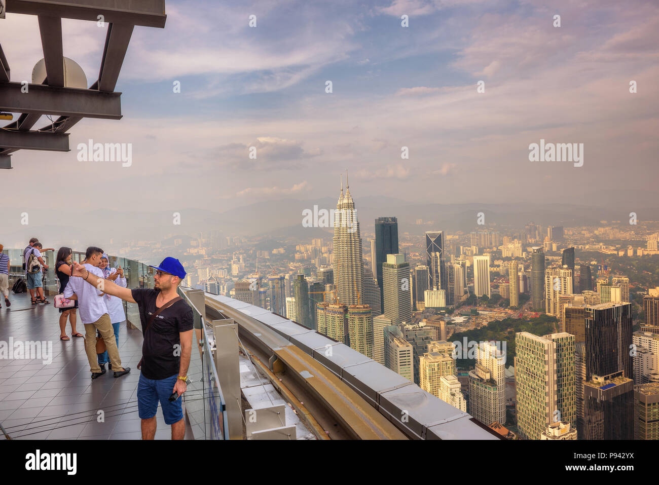 I visitatori sulla sommità della Menara KL Tower con vista del Kuala Lumpur skyline Foto Stock