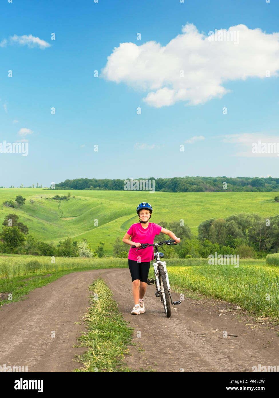 Ragazza sportiva con la bicicletta nel campo verde. Foto Stock