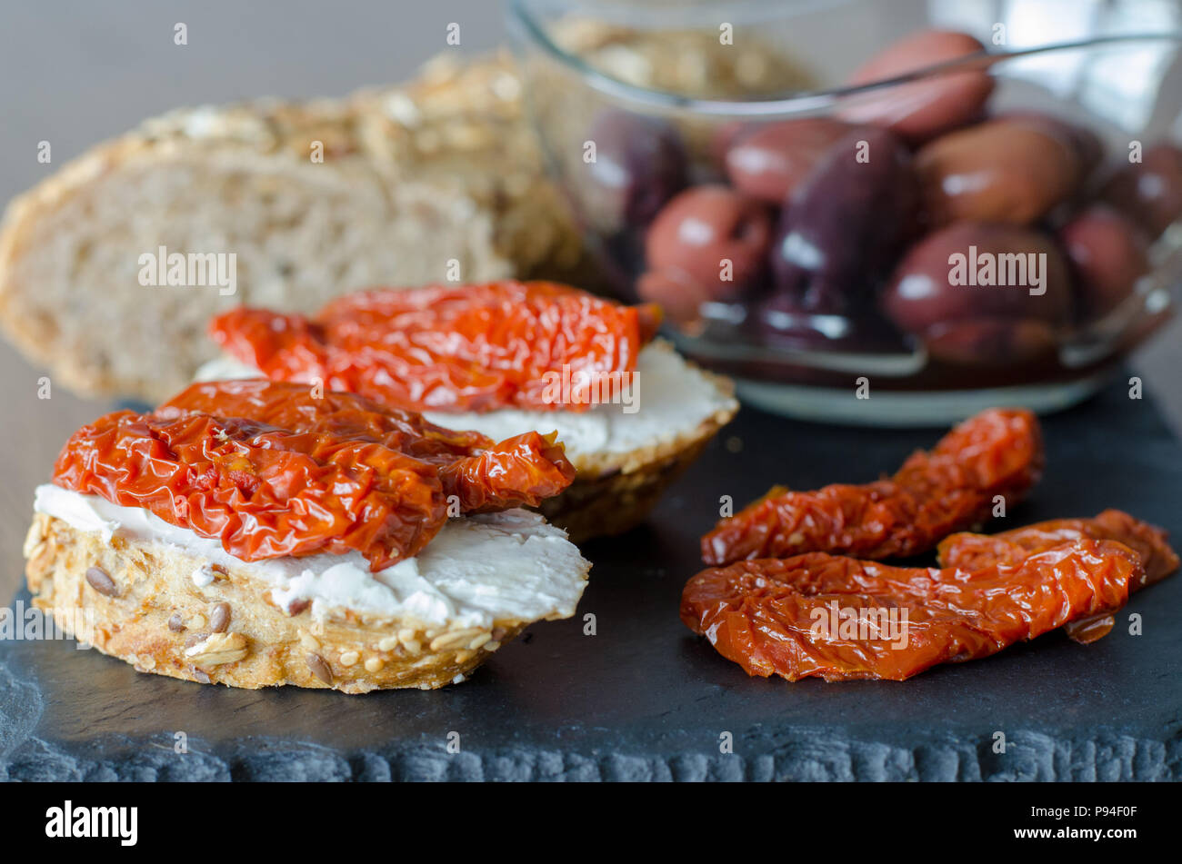 Bruschetta con pomodori secchi e formaggio a pasta morbida con ebollizione di olive. La cucina tradizionale italiana sandwich. Antipasti Foto Stock