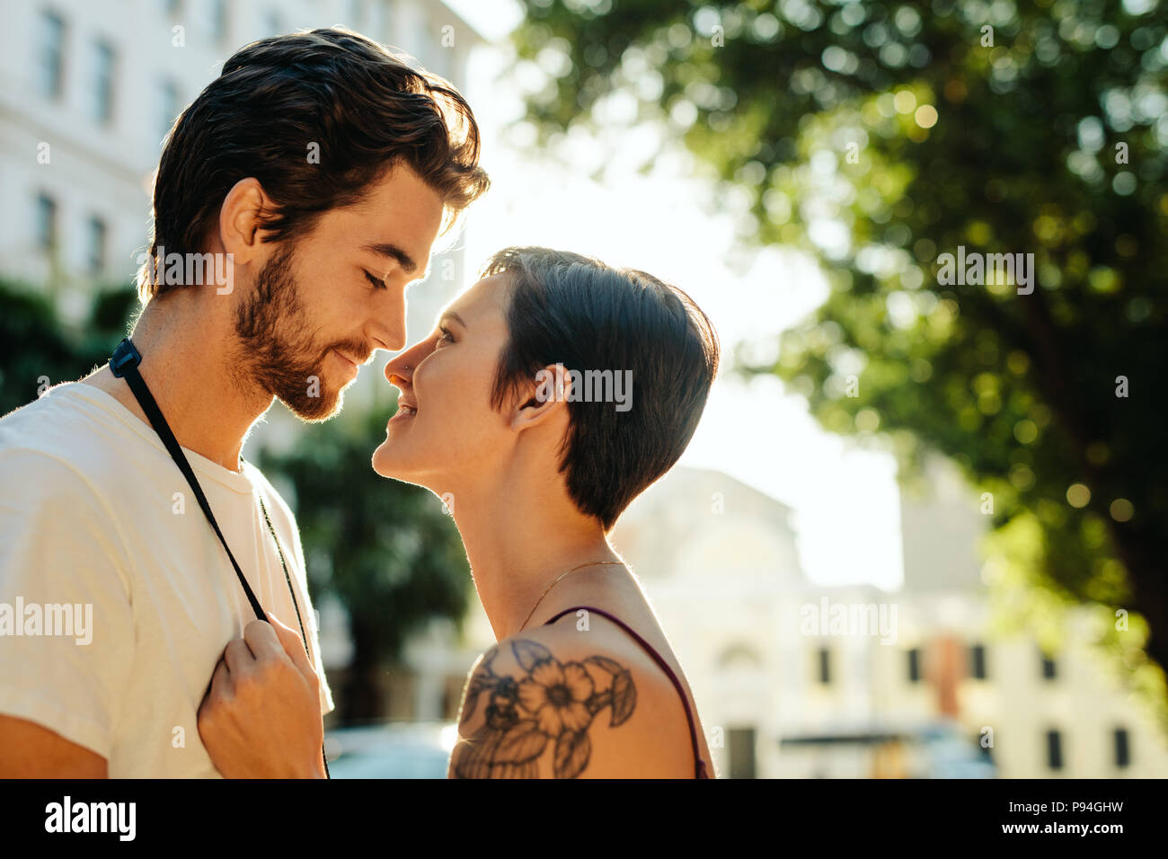 Donna in piedi vicino ad un uomo che sta per baciare permanente sulla strada. Turista giovane in una felice e umore romantico mentre ad esplorare la città. Foto Stock