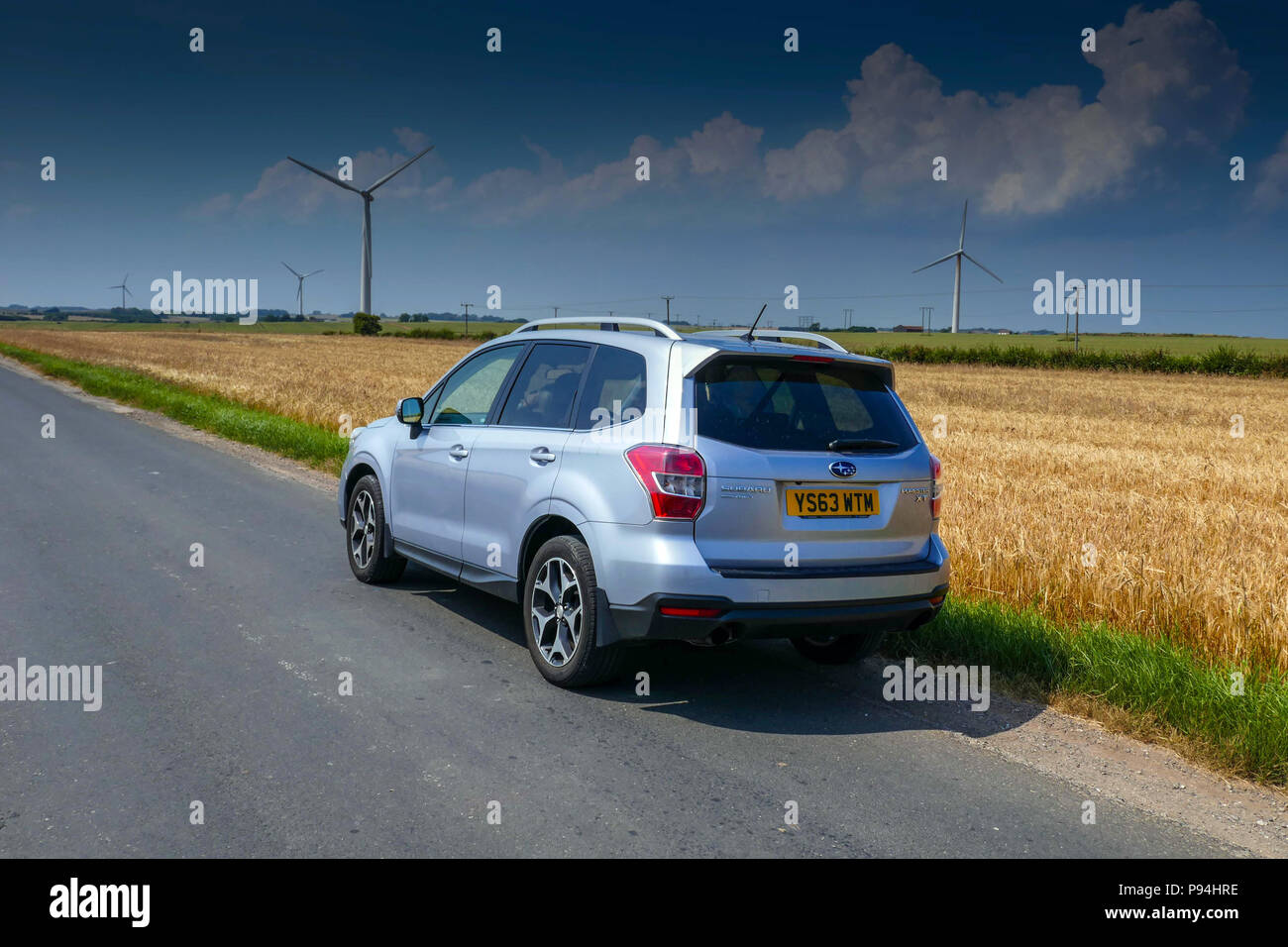 Subaru Forester 4 x 4 e delle turbine a vento e seminativi in campi, Holderness, vicino a Hull, East Yorkshire Foto Stock