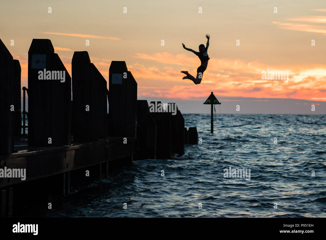 Aberystwyth Wales UK, sabato 14 luglio 2018 UK Meteo: giovani il salto in mare al largo del molo al fine di ancora un altro giorno di ininterrotta sole estivo in Aberystwyth sulla costa occidentale del Galles. Il lungo periodo di caldo e insolitamente secco meteo continua, con temperature sempre salendo ad oltre 30ºC in parti del Regno Unito questo weekend Photo credit: Keith Morris / Foto Stock