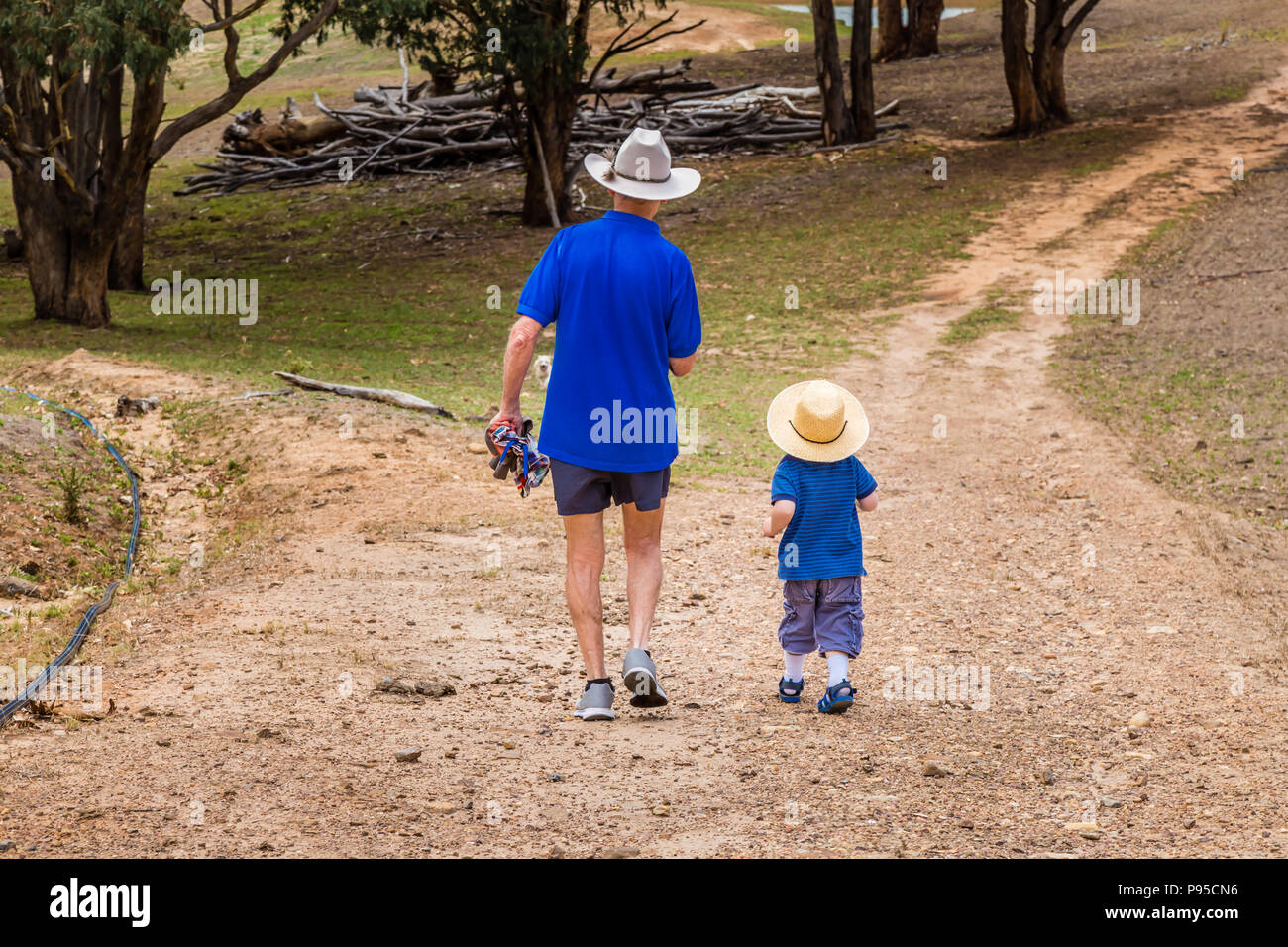 Piccolo Ragazzo a piedi attraverso la campagna Australiana con il suo nonno. Foto Stock