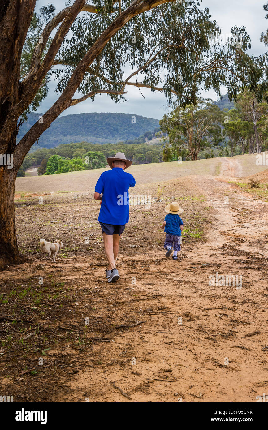 Piccolo Ragazzo a piedi attraverso la campagna Australiana con il suo nonno. Foto Stock