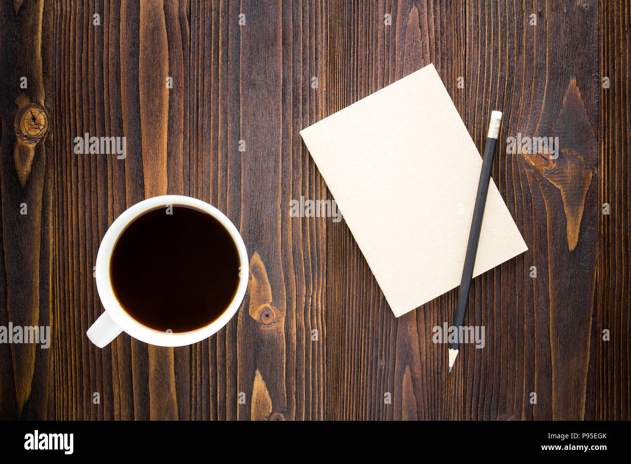 White tazza di caffè con caffè nero ,notebook e matita su un tavolo di legno. Foto Stock