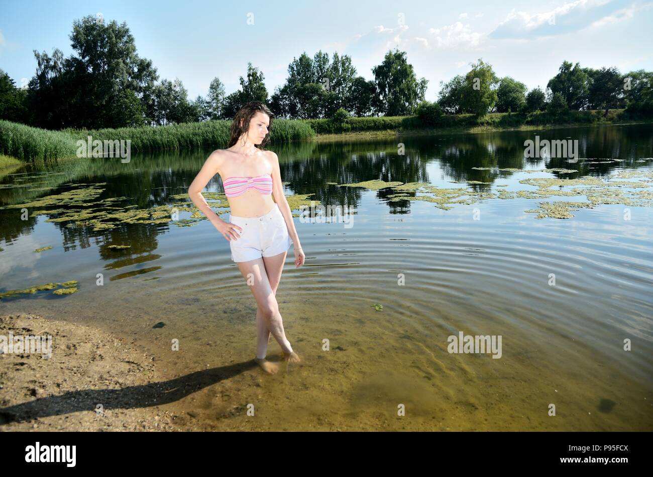 Giovani modello femminile in outdoor sessione fotografica in Polonia.  Ragazza in pantaloni corti e bikini top con peli bagnati sorge nel lago  Foto stock - Alamy