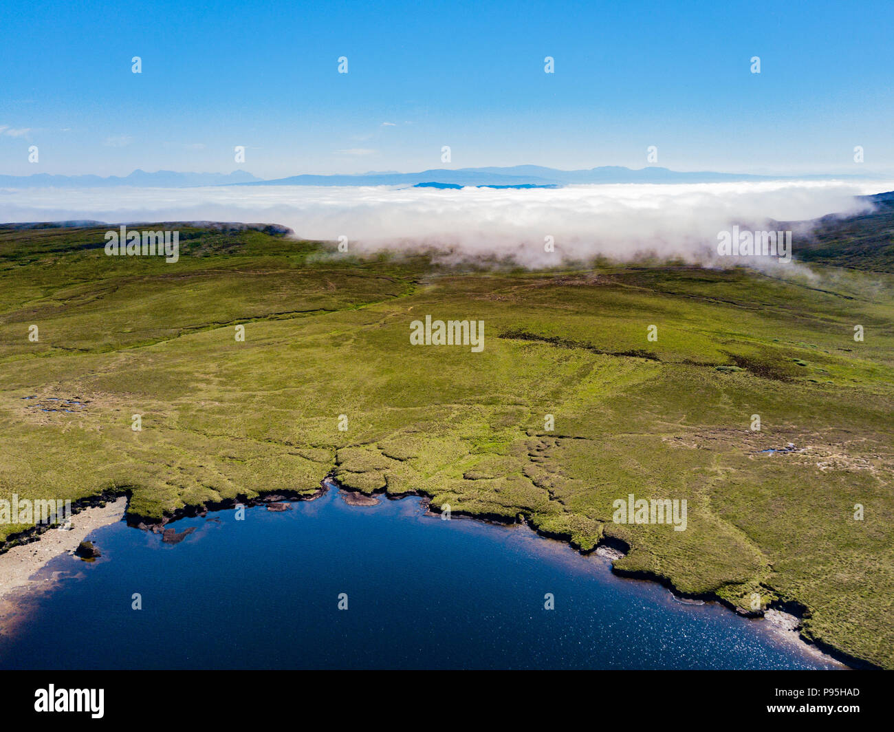 Un basso livello di nebbia i rotoli su un loch sull'Isola di Skye Foto Stock