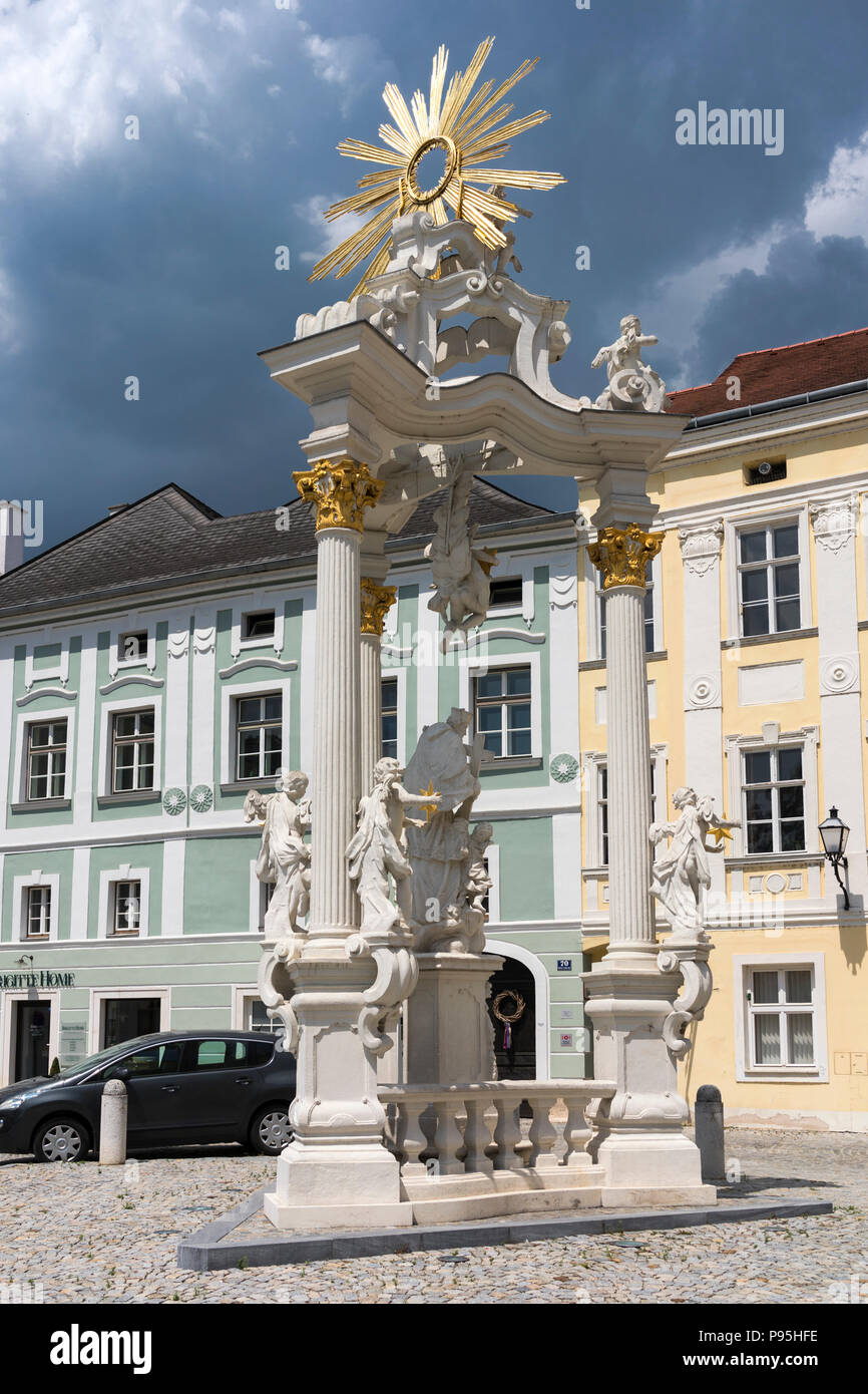 Il Golden Sun del Dreifaltigkeitssäule (Colonna della Santa Trinità) contrastante contro un cielo tempestoso in Stein an der Donau, Austria inferiore Foto Stock
