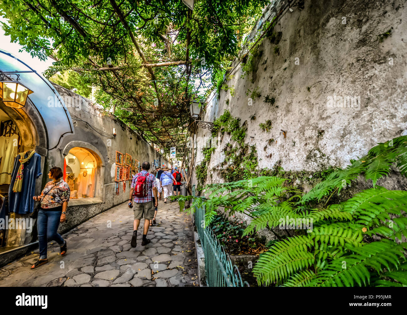 Finestra di turisti shop su un pittoresco stretto vicolo coperto di edera, al riparo dal sole a Positano Italia sulla costiera del Mediterraneo Foto Stock